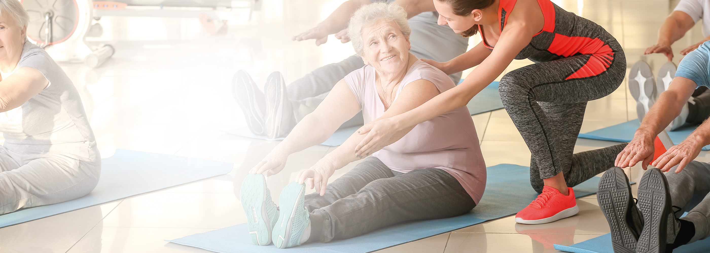 Une monitrice de sport de Pro Senectute montre des exercices au sol à une personne âgée.