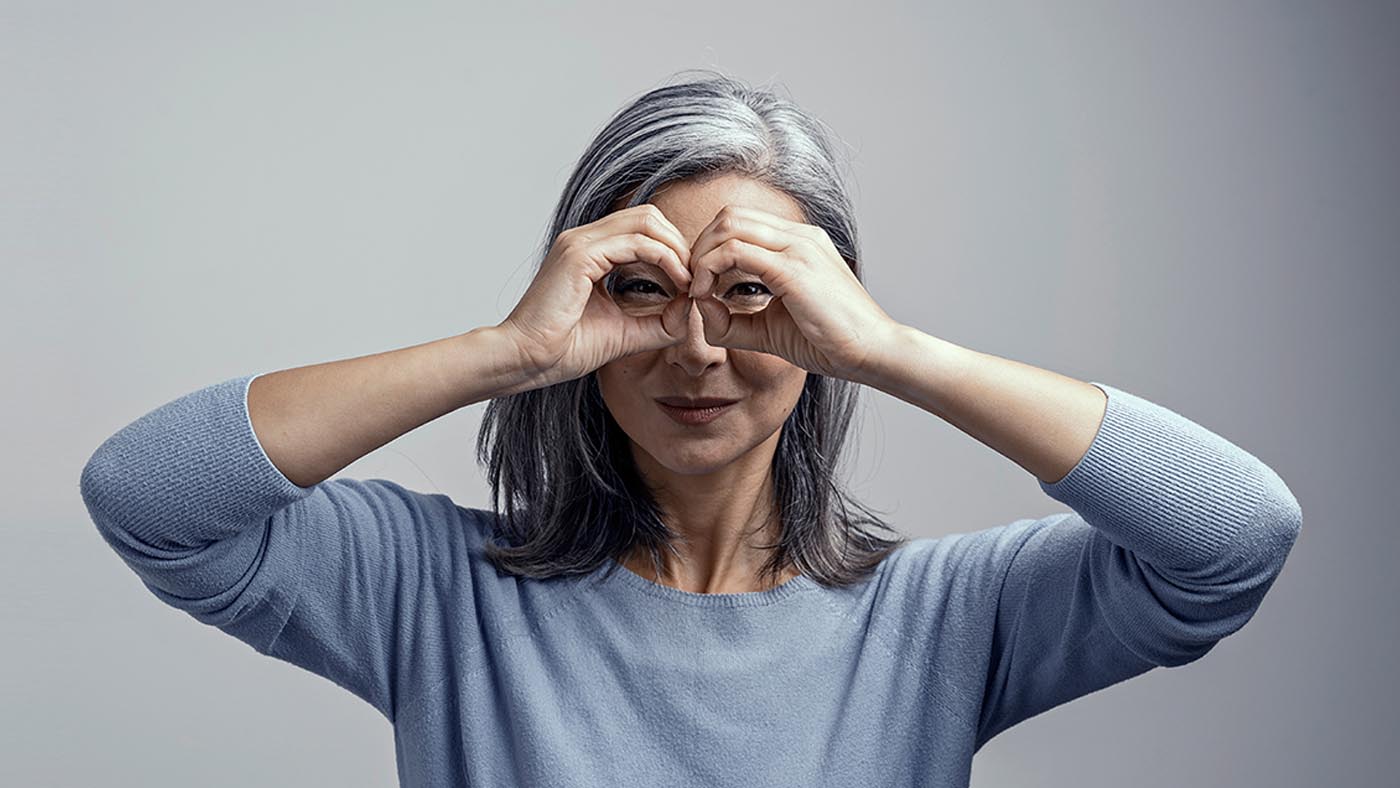 Une femme tient ses mains au-dessus de ses yeux comme des jumelles.